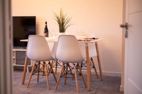 a table with three white chairs and a table with wine glasses at Walnut Flat, 2-Bedroom with Ensuite - Parking, Netflix, WIFI - Close to Oxford, Bicester & Blenheim Palace - F4 in Oxford