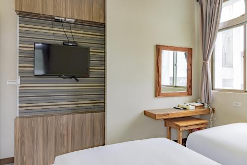 1 dormitorio con 1 cama y TV en la pared en Star-Moon B&B Green Island en Green Island