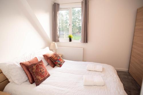 een slaapkamer met een wit bed met kussens en een raam bij Walnut Flats-F4, 2-Bedroom with Ensuite - Parking, Netflix, WIFI - Close to Oxford, Bicester & Blenheim Palace in Kidlington