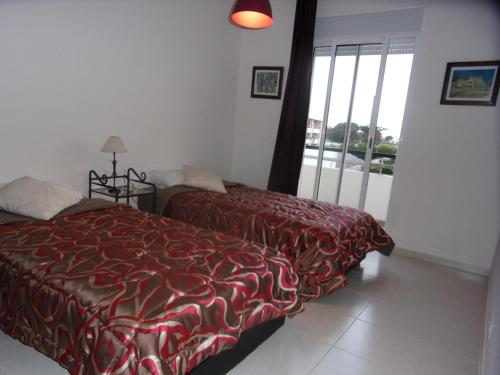1 dormitorio con 2 camas y ventana grande en Bahia Golf Beach Bouznika appart, en Bouznika