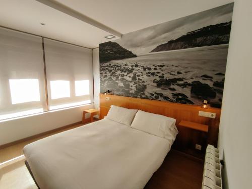 1 dormitorio con 1 cama y una pintura en la pared en Hotel Dabeleira, en Luarca