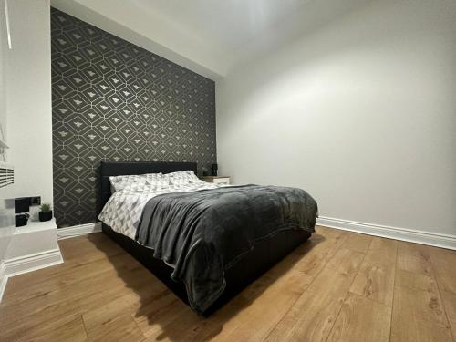 een slaapkamer met een bed met een zwarte muur bij Bee Accommodations in Leicester