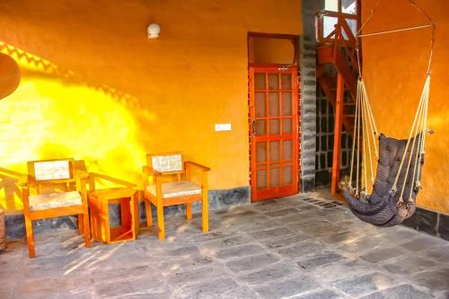 a room with chairs and a hammock in a house at Prakriti Aalay - Riverside Mountain View Boutique Eco Resort in Dharamshala