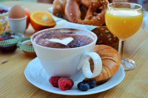 a cup of coffee and a croissant and a glass of orange juice at Landhaus Riedl in Bad Füssing