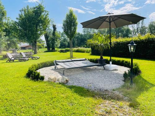 a bench with an umbrella in a park at Landhaus Riedl in Bad Füssing