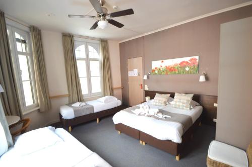 a bedroom with two beds and a ceiling fan at Hotel Ambrosia in Ypres