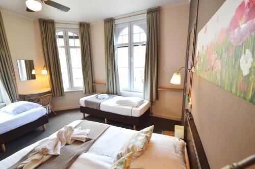 a hotel room with two beds and two windows at Hotel Ambrosia in Ypres