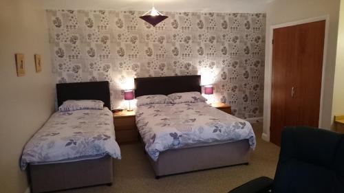 a bedroom with two beds and two tables with lamps at Moorland House in York