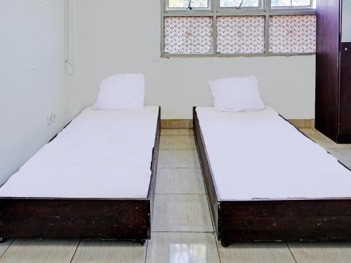 2 camas individuales en una habitación con ventana en SPOT ON 92374 Penginapan Rusunawa, en Malang