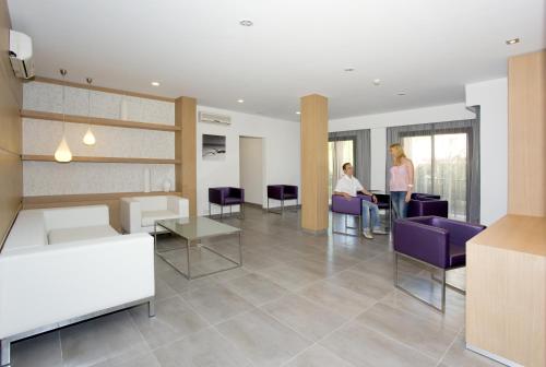 two women standing in a lobby with purple chairs and tables at Hotel Morlans in Paguera