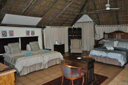 a bedroom with two beds and a table and a desk at Cashan BnB in Rustenburg