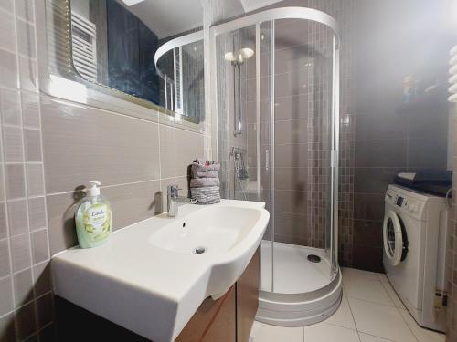 a bathroom with a sink and a washing machine at Central Apartments Garnizon 928 & Parking in Gdańsk