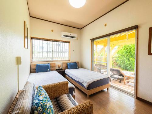 a bedroom with two beds and a balcony at Panorama in Yomitan