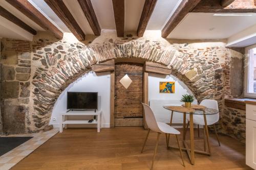 Habitación con pared de piedra, mesa y sillas. en Cosylocation - Chaleureux - Hypercentre, en Vienne