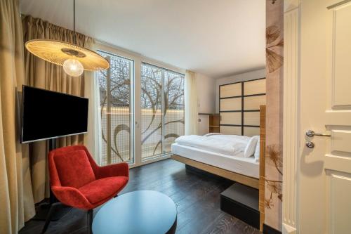 une chambre d'hôtel avec un lit et un fauteuil rouge dans l'établissement Villa Steiner 5 - Suzuka, à Merano