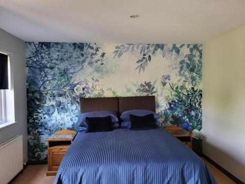 a bedroom with a blue bed with a floral wallpaper at The Garden Rooms at Tannery House in Bakewell