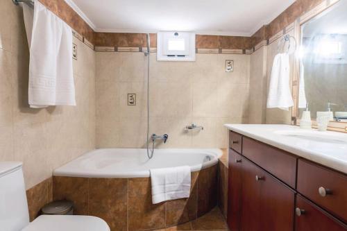 a bathroom with a tub and a toilet and a sink at Villa Panthea in Keratokampos