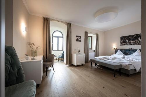 a bedroom with a bed and a desk and a chair at Schloss Plars wine & suites in Lagundo