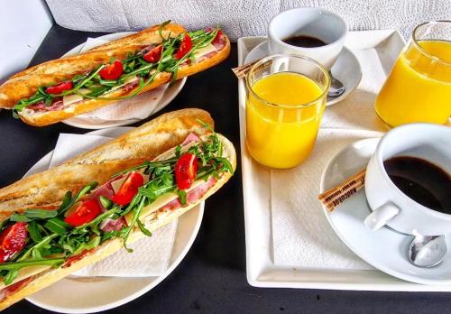 two sandwiches on plates on a table with coffee and orange juice at Mátyás Corner Apartments Green Square Studio Apartment II in Budapest