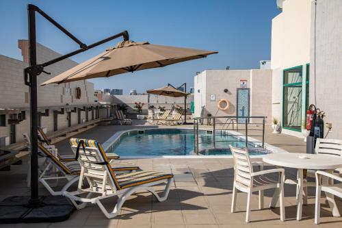 a patio with chairs and an umbrella and a pool at Wescott Pearl Hotel Apartments in Dubai