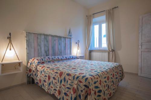 ein Schlafzimmer mit einem Bett mit einer farbenfrohen Tagesdecke und einem Fenster in der Unterkunft HelloElba Appartamento Il Mediceo in Portoferraio
