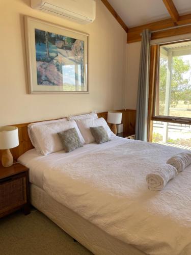 - une chambre avec un grand lit blanc et une fenêtre dans l'établissement Warby Cottage, à Wangaratta