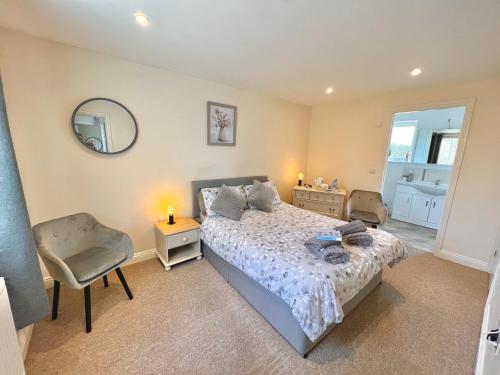 1 dormitorio con cama, silla y espejo en Webbys Windrush Walk, en Bourton on the Water