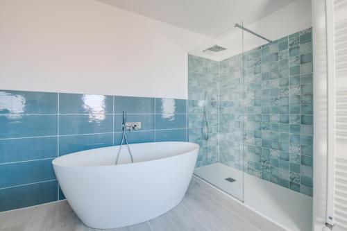a bath tub in a bathroom with blue tiles at A terrace on the lake of Lugano in Aldesago