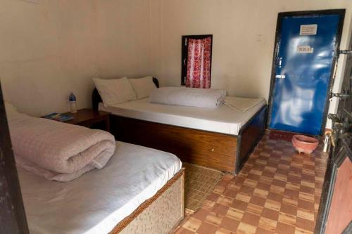 a room with two beds and a window at Ayodhyapuri Community Homestay in Chitwan