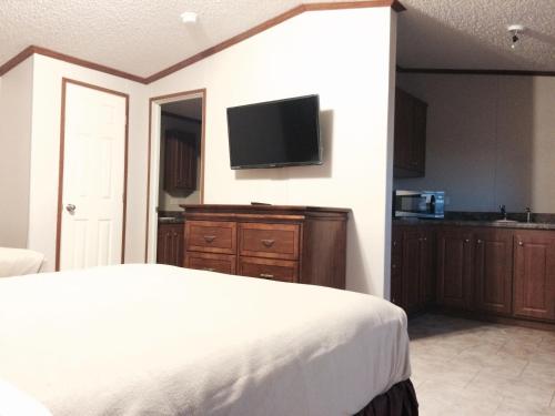 1 dormitorio con 1 cama y TV de pantalla plana en Oasis Lodge, en Big Lake
