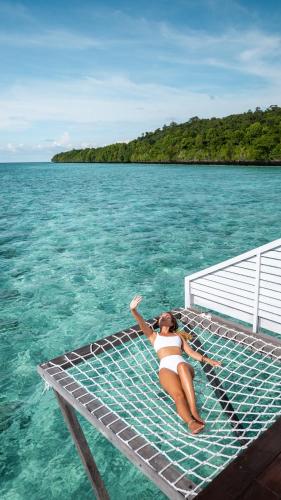 a woman laying on a raft in the water at Arasatu Villas & Sanctuary in Maratua Atoll