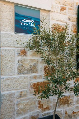 a plant in front of a sign on a brick wall at Vive Mar Paxos in Gaios