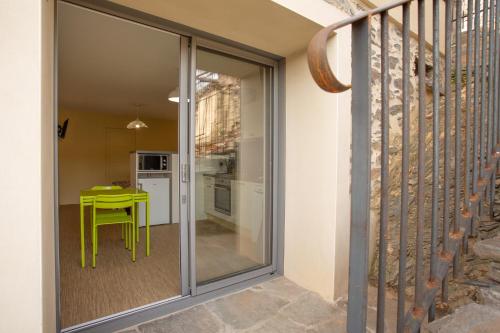 a glass door leading into a kitchen with a green table at Appartement - gîte de la Moulinquié in Saint-Cirgue