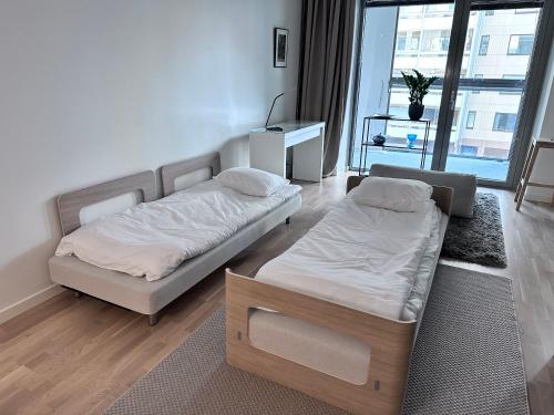 two beds in a room with a window at Peaceful Premium Apartment with Sauna and Balcony - Perfect Downtown Location in Tampere