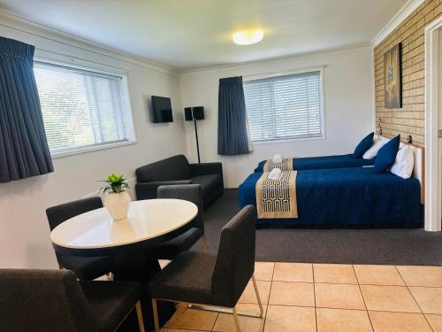 a bedroom with a bed and a table and chairs at Leichhardt Motor Inn in Toowoomba