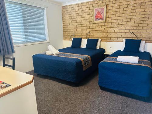 a bedroom with two beds and a brick wall at Leichhardt Motor Inn in Toowoomba