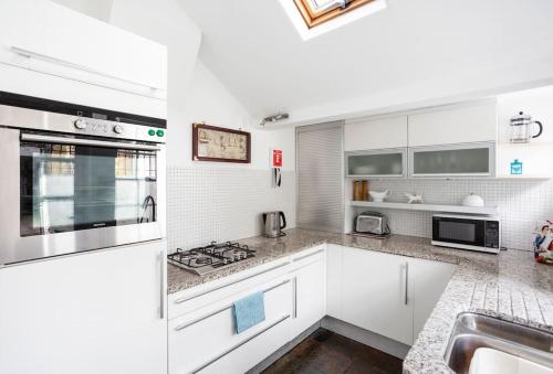 a white kitchen with white cabinets and a sink at Old Anchor Cottage, Broadstairs. in Broadstairs