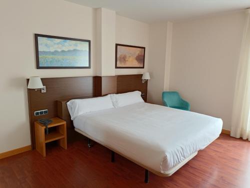 a bedroom with a white bed and a blue chair at Hotel Palacio Congresos in Palencia