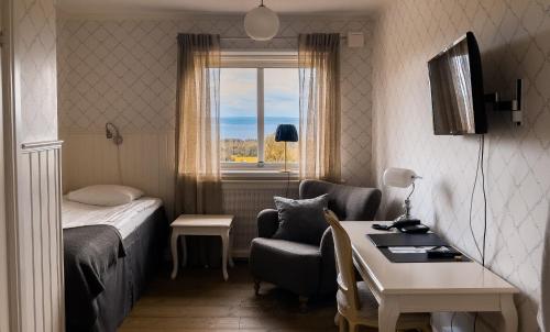 Cette chambre comprend un lit, un bureau et une fenêtre. dans l'établissement Hotell Villa Långbers, à Tällberg