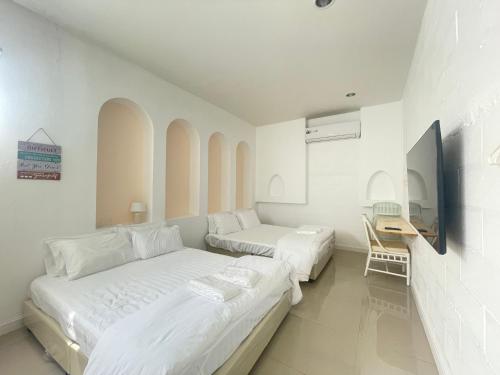 a white bedroom with two beds and a desk at มินิมอลโฮลเทล in Ban Khlong Khachen