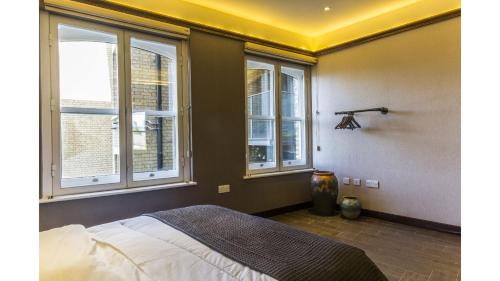 um quarto com janelas e uma cama em Pass the Keys Spacious Luxury Apartment in the Heart of London em Londres