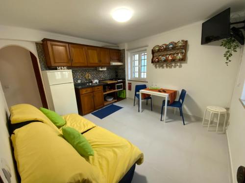 een keuken met een tafel en een geel bed in een kamer bij O Cabaça in Sesimbra