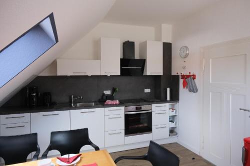 uma cozinha com armários brancos e uma mesa com cadeiras em Ferienwohnung Woldemar em Detmold