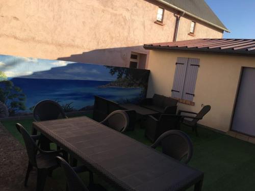 une terrasse avec une table et des chaises ainsi qu'une fresque murale. dans l'établissement Maison de ville, à Romorantin-Lanthenay