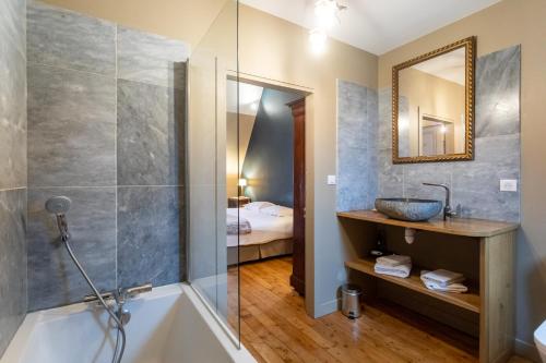 a bathroom with a tub and a sink and a mirror at L' Hotel de Panette, entrée Renaissance Cathédrale in Bourges