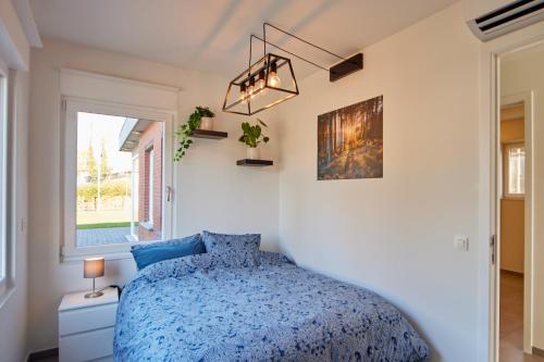 a bedroom with a blue bed and a window at Holiday Home De Steenen Molen in Brecht