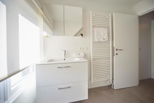 a white bathroom with a sink and a mirror at Holiday Home De Steenen Molen in Brecht