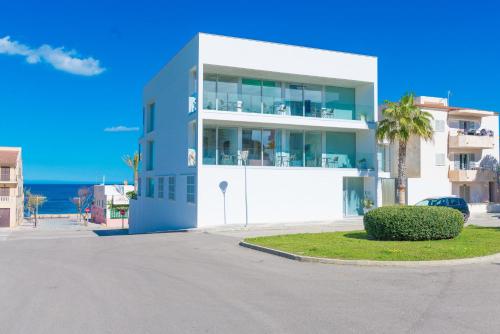un edificio azul y blanco con una palmera y el océano en Villa Mar 18, en Can Picafort