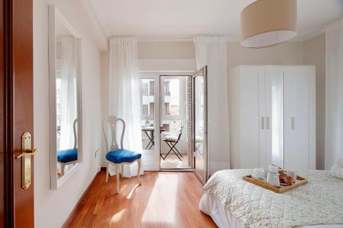 a white bedroom with a bed and a table at 115A - Amplia vivienda en Playa San Lorenzo in Gijón