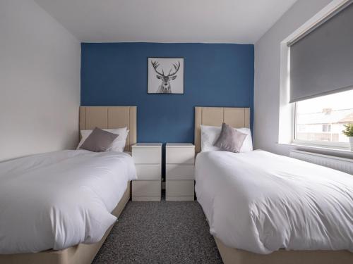2 camas en una habitación con paredes azules en Pass the Keys Spacious house with free parking, en Doncaster
